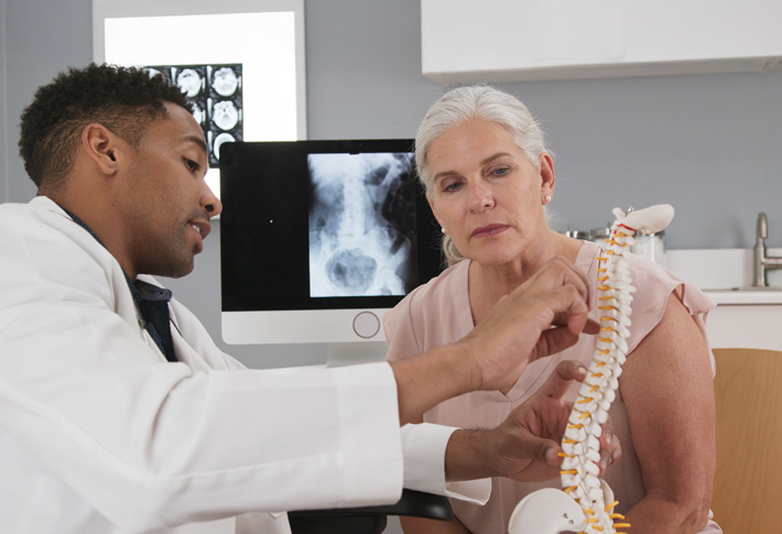 Doctor discussing the spine with a patient using spine model